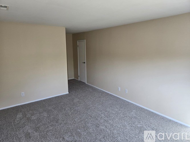A room with a carpeted floor and a door in the background.