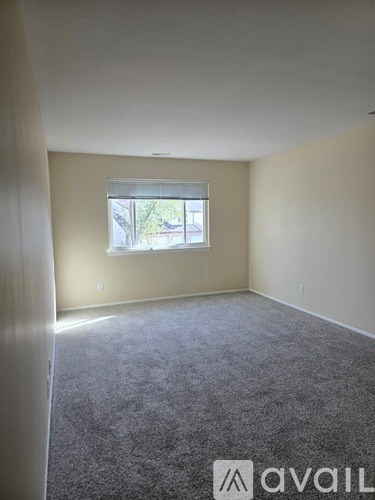 A carpeted room with a window and Avail logo.