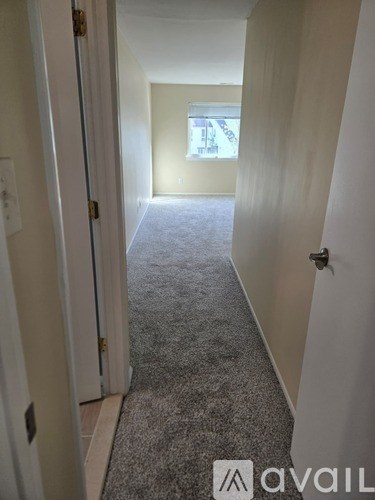 A hallway with a carpeted floor and white walls.