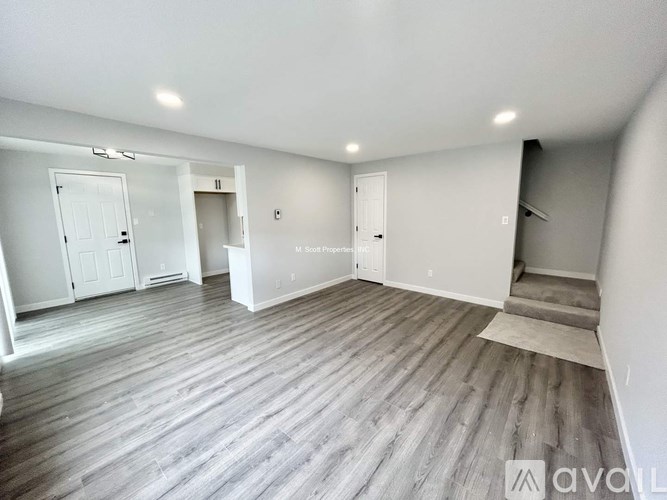 A spacious room with wooden flooring and white walls.