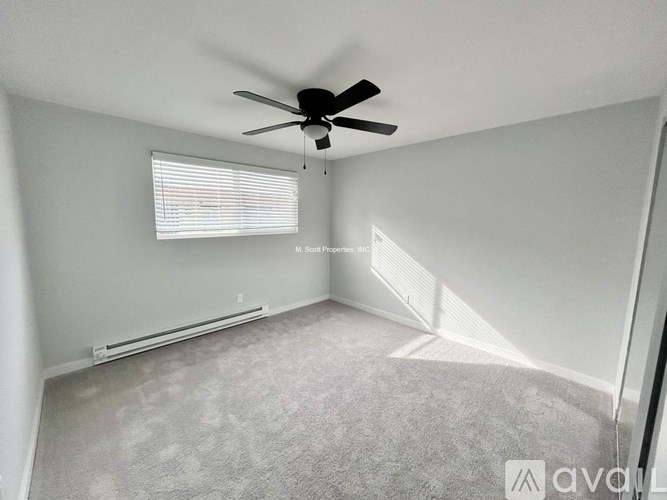 A room with a ceiling fan and a window with blinds.