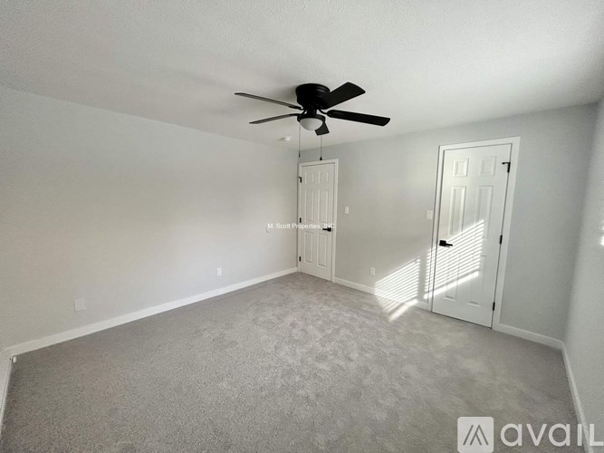 A room with a ceiling fan and carpeted floor.