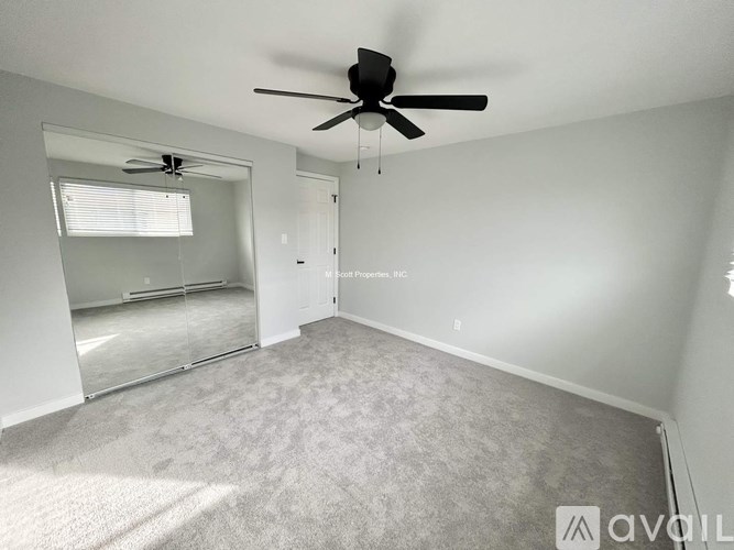 A room with a ceiling fan and carpeted floor.
