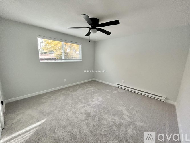 A room with a ceiling fan and a window with blinds.