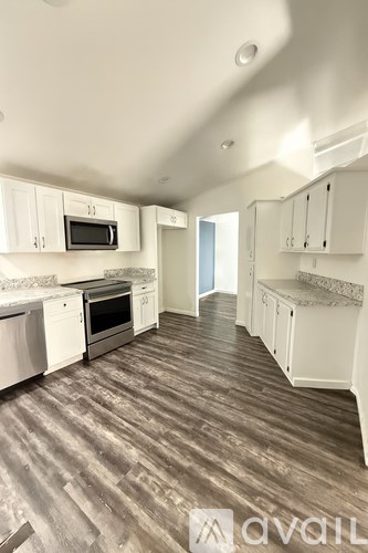 A kitchen with white cabinets and a wooden floor.