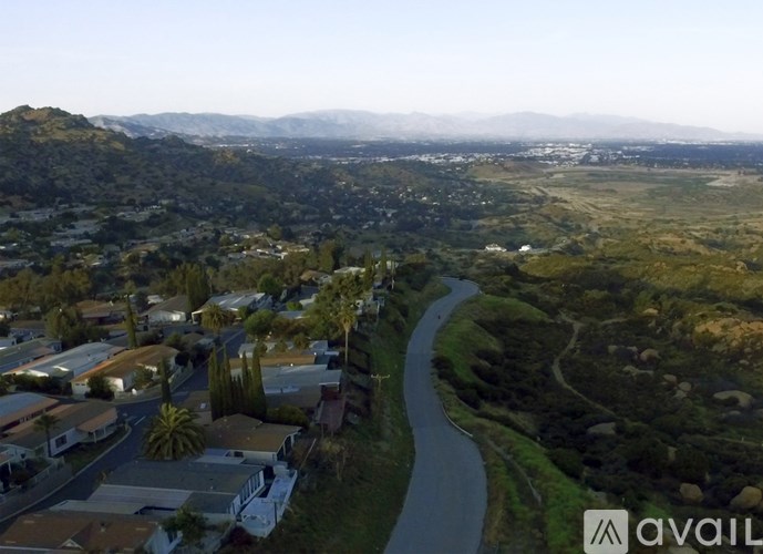 A river flows through a valley with houses on the left and mountains in the distance.