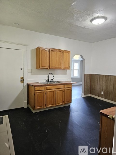 A kitchen with wooden cabinets and black flooring.