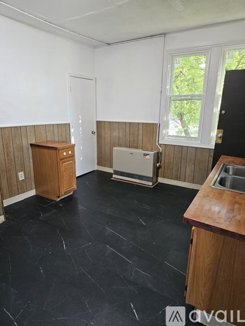 A kitchen with black tile flooring and wooden cabinets.