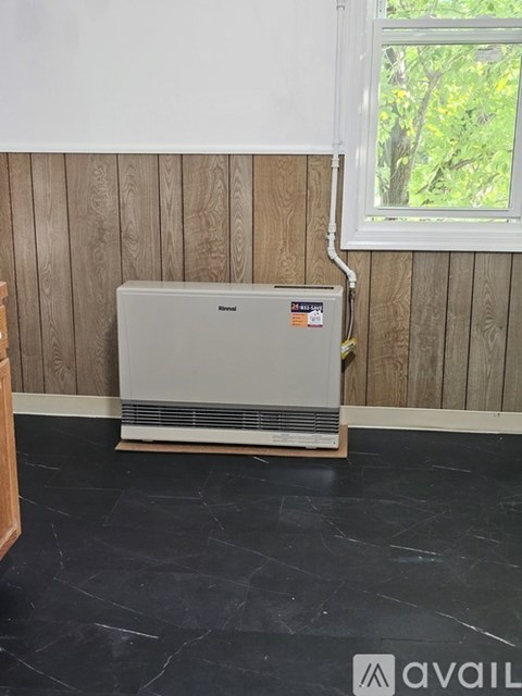A wall heater is installed in a room with wooden walls and black marble flooring.