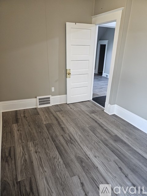 A room with a white door and wooden flooring.
