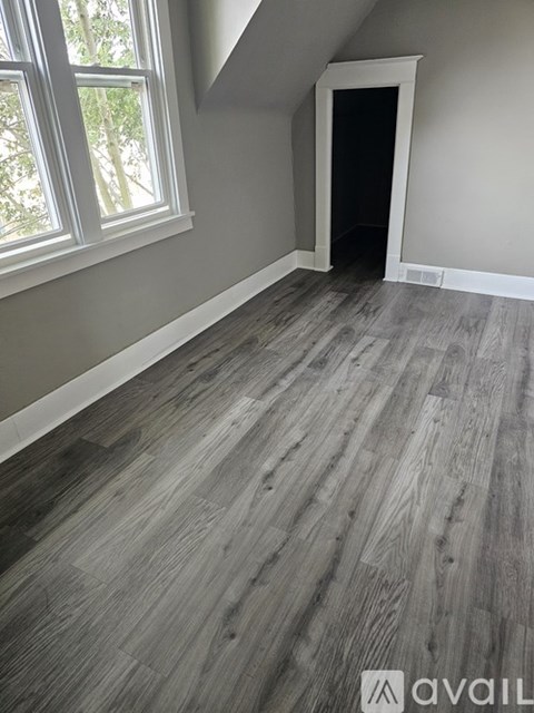 A room with a grey wooden floor and a window.