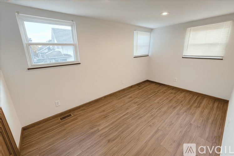 A room with wooden flooring and two windows.