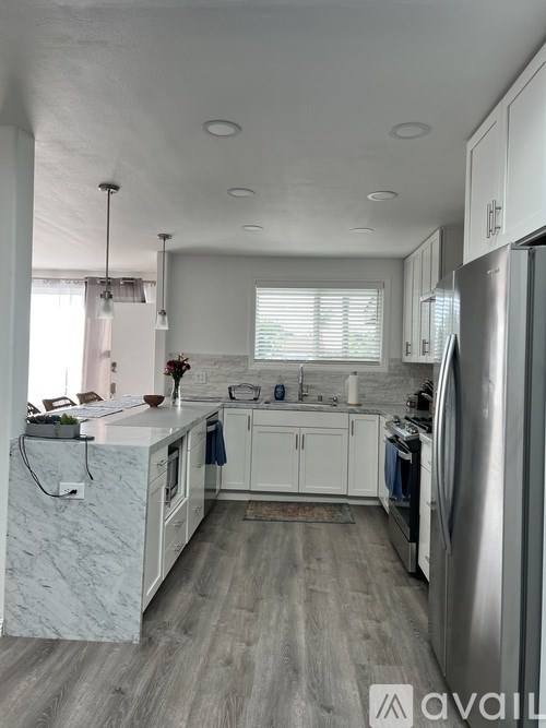 A kitchen with a refrigerator, sink, and cabinets.