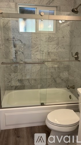 A bathroom with a marble wall and a glass shower door.