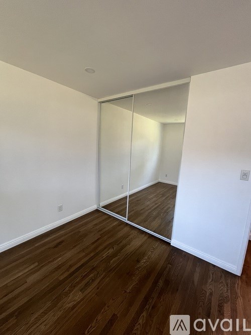 A room with a white wall and a wooden floor.