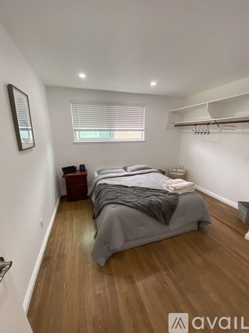 A bedroom with a bed, nightstand, and window with blinds.