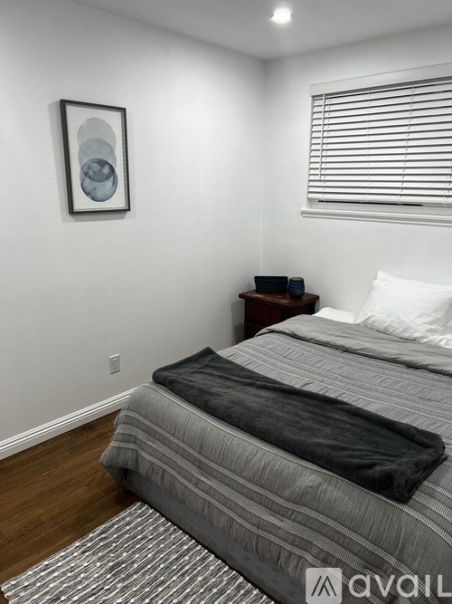 A bedroom with a bed, nightstand, and a picture on the wall.