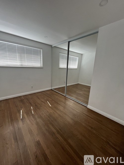A room with wooden flooring and a large mirror.