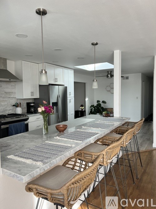 A modern kitchen with a marble countertop and stainless steel appliances.