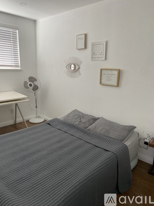 A bedroom with a bed, a fan, and a window with blinds.