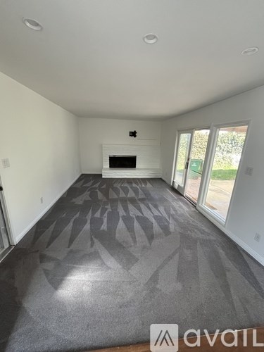 A living room with a fireplace and a rug with a leaf pattern.