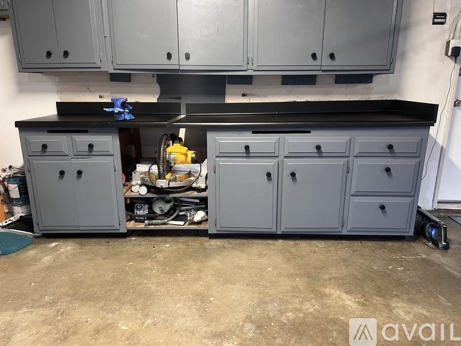 A workshop with grey cabinets and a black countertop.