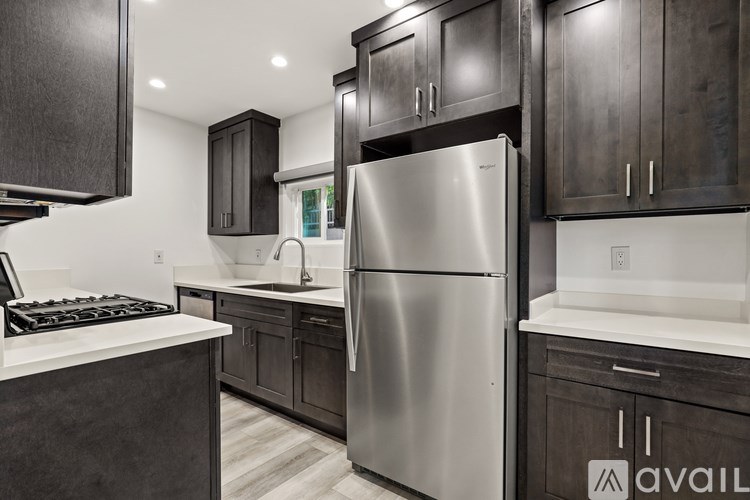 A modern kitchen with dark wood cabinets and a stainless steel refrigerator.