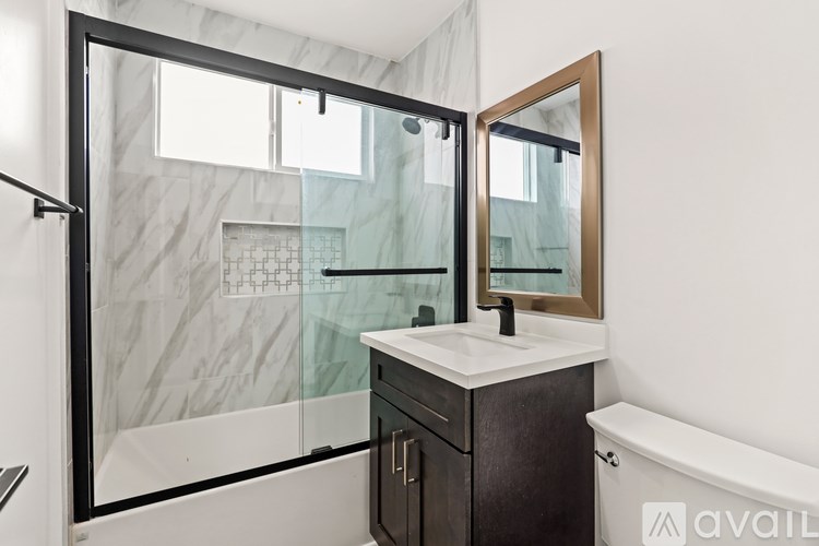 A bathroom with a marble wall and a glass shower door.