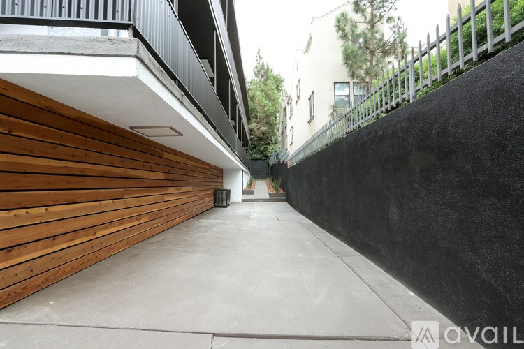 A long, narrow alley with a wooden wall on the left and a black wall on the right.