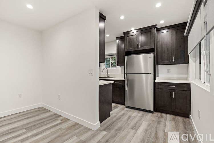 A kitchen with a refrigerator, cabinets, and a countertop.