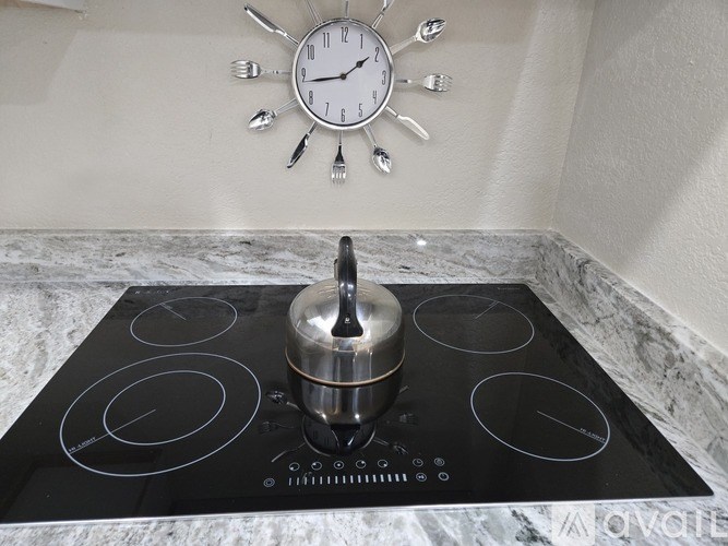 A stove top with a pot on it and a clock above it.