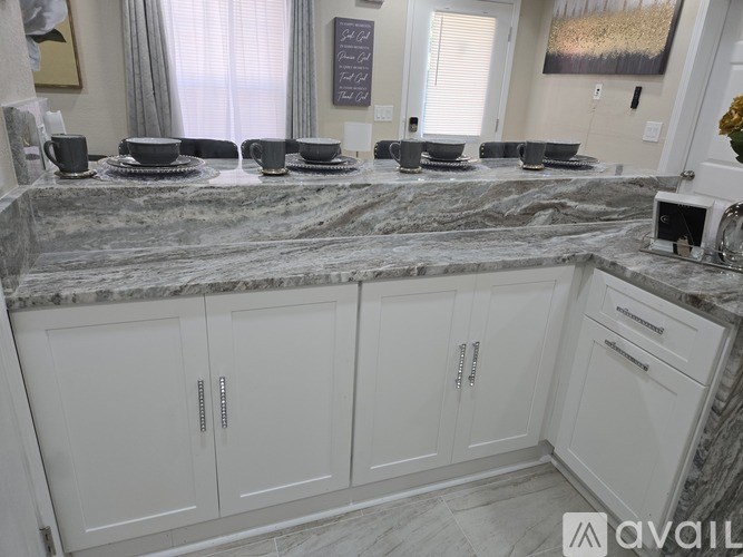 A kitchen with marble countertops and white cabinets.
