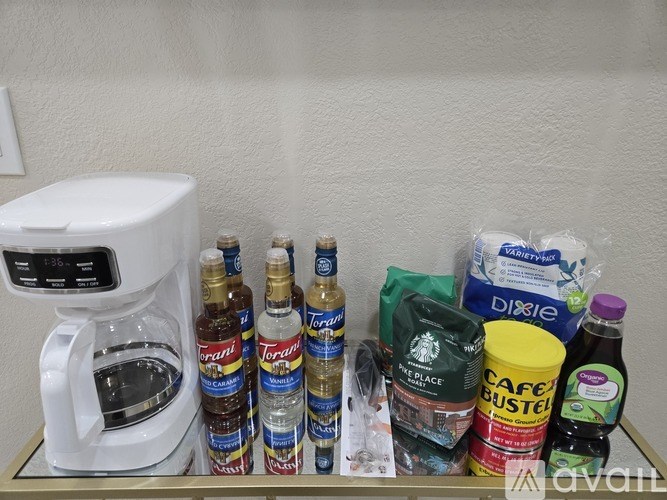 A coffee maker and several bottles of Torani syrup are on a counter.