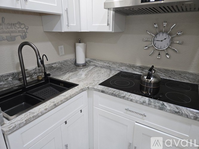 A kitchen with a marble countertop and a stainless steel stove top.
