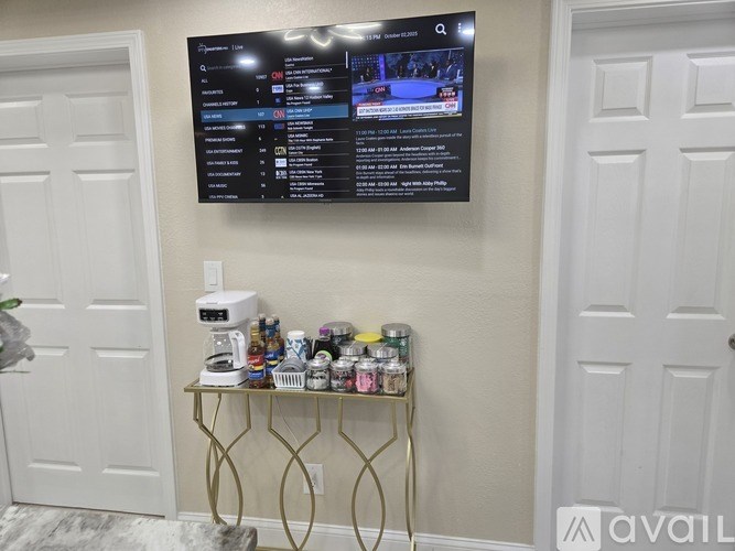 A black menu board is mounted on a wall above a gold table with a coffee maker and various cans on it.