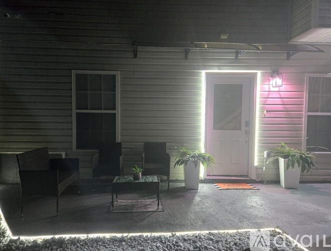 A patio with a table and chairs is lit by a pink light.