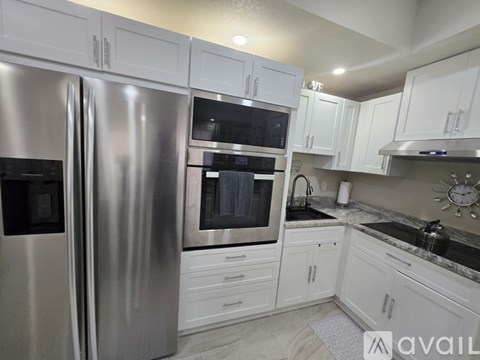 A kitchen with a stainless steel refrigerator and white cabinets.