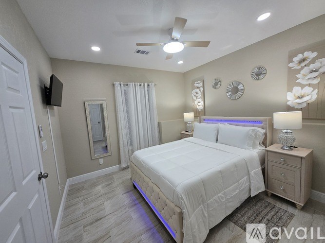 A well-lit bedroom with a large bed, a ceiling fan, and a nightstand with a lamp.