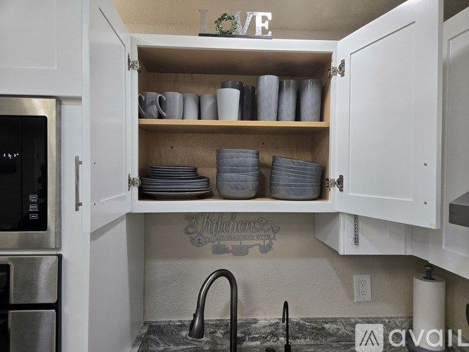 A kitchen with a shelf containing plates and cups.