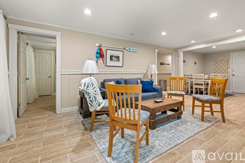 A living room with a blue couch and wooden chairs.
