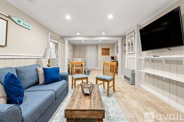 A living room with a grey couch, wooden coffee table, and a flat screen TV mounted on the wall.