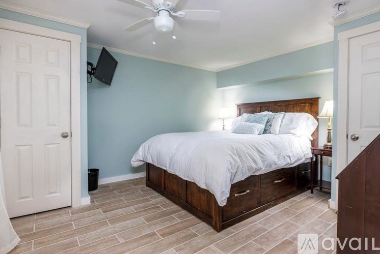 A bedroom with a bed, nightstand, and a ceiling fan.