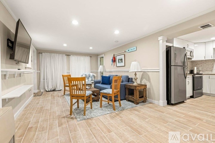 A living room with a television, a couch, a chair, and a dining table.