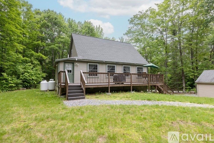 A house with a deck and a green roof is surrounded by trees.