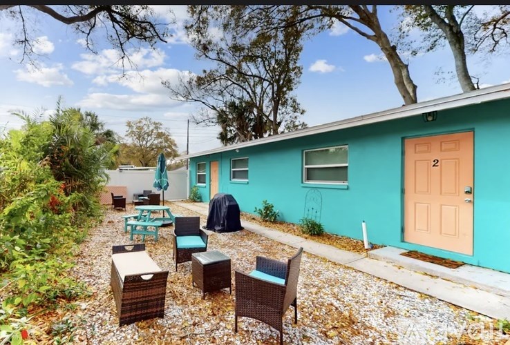 A blue house with a brown door and a patio with chairs and a table.
