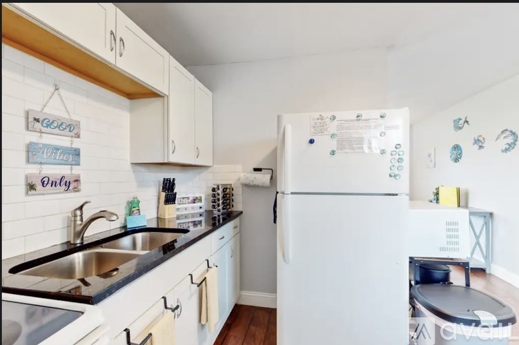 A kitchen with a white fridge and a white sink.