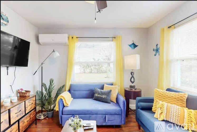 A living room with a blue sofa and yellow pillows.