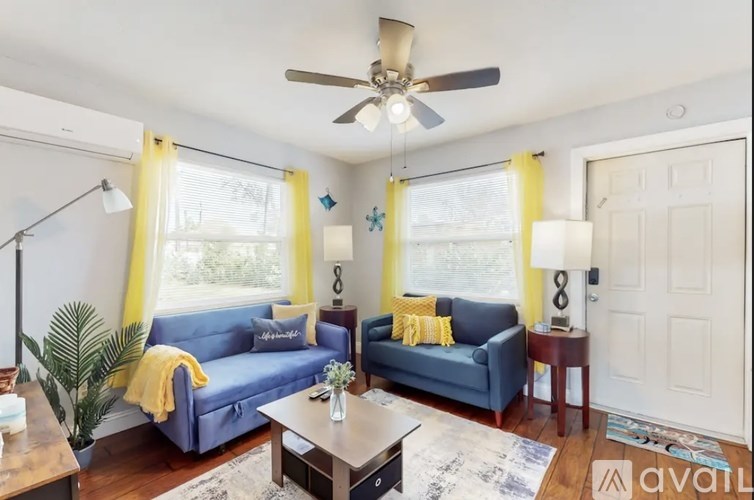 A living room with a blue couch and yellow curtains.