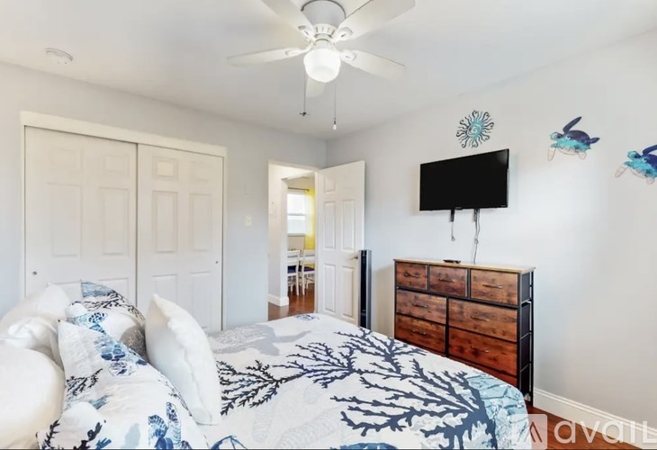 A bedroom with a bed, dresser, and ceiling fan.
