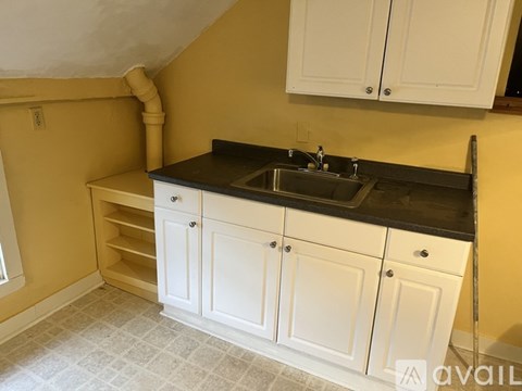 A kitchen with white cabinets and a black countertop.